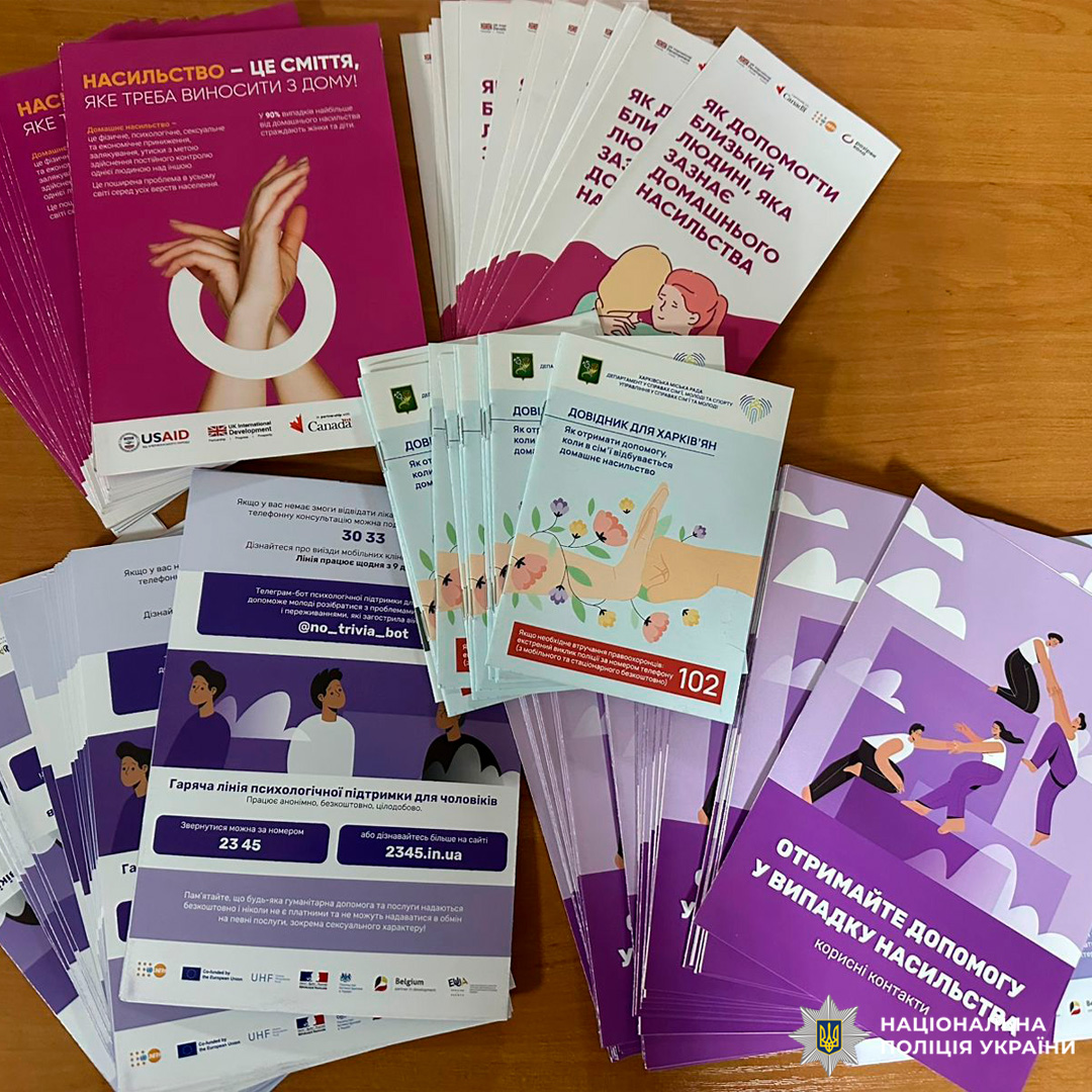 Інформаційні буклети на тему протидії домашньому насильству розкладені на дерев’яній поверхні.
