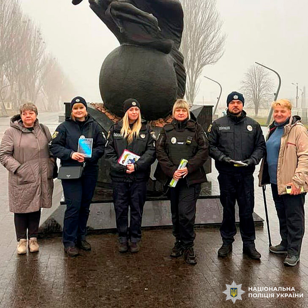 Шестеро людей біля скульптури на вулиці; четверо у формі Нацполіції України, двоє цивільні. Поліцейські тримають інформаційні матеріали.