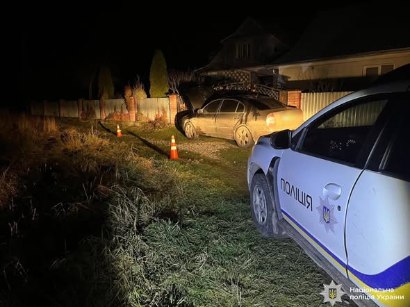 Темна пора доби. Поліцейський автомобіль  біля транспорного засобу, чорного кольору, який намагалися підпалити