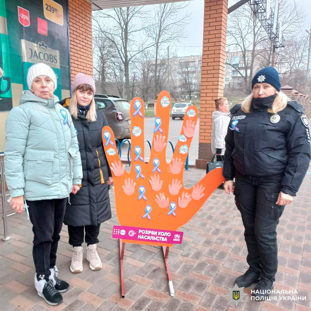 Учасники заходу з поліцейською  біля інсталяції «Розірви коло насильства» біля торгового закладу.