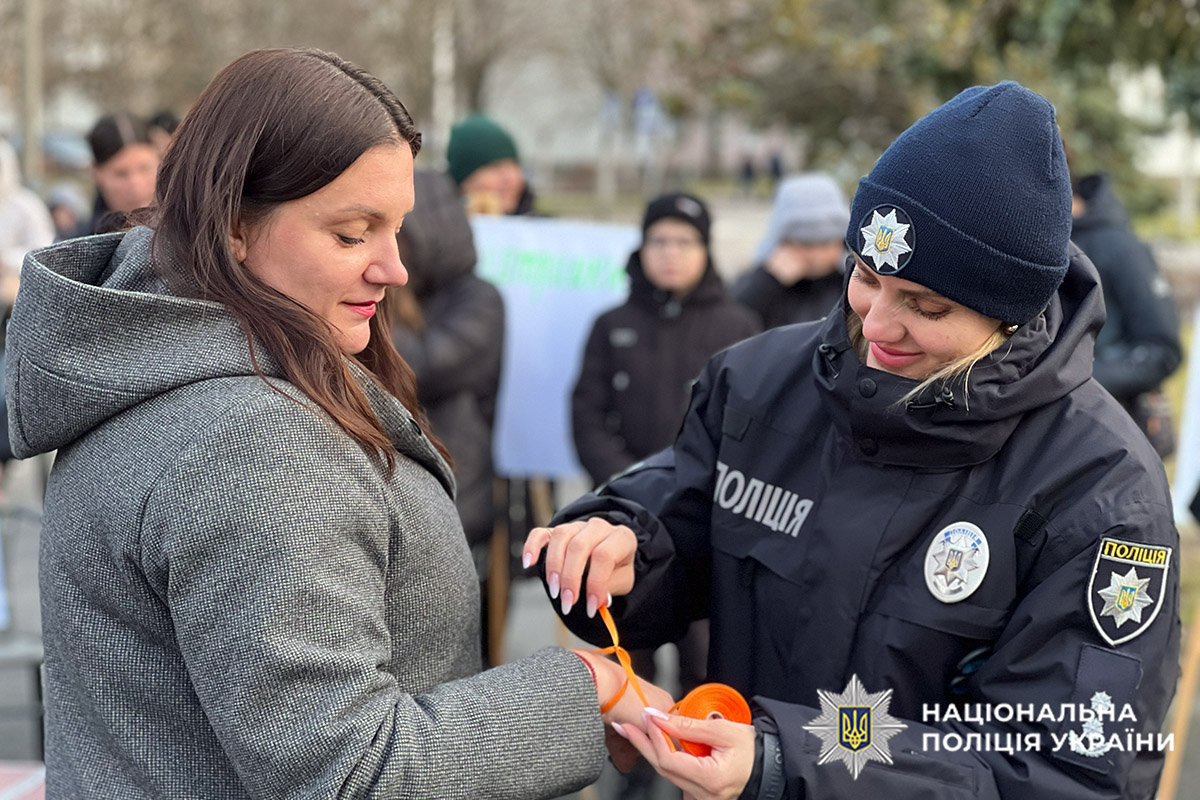 Поліцейська пов’язує символічну стрічку на руку жінки