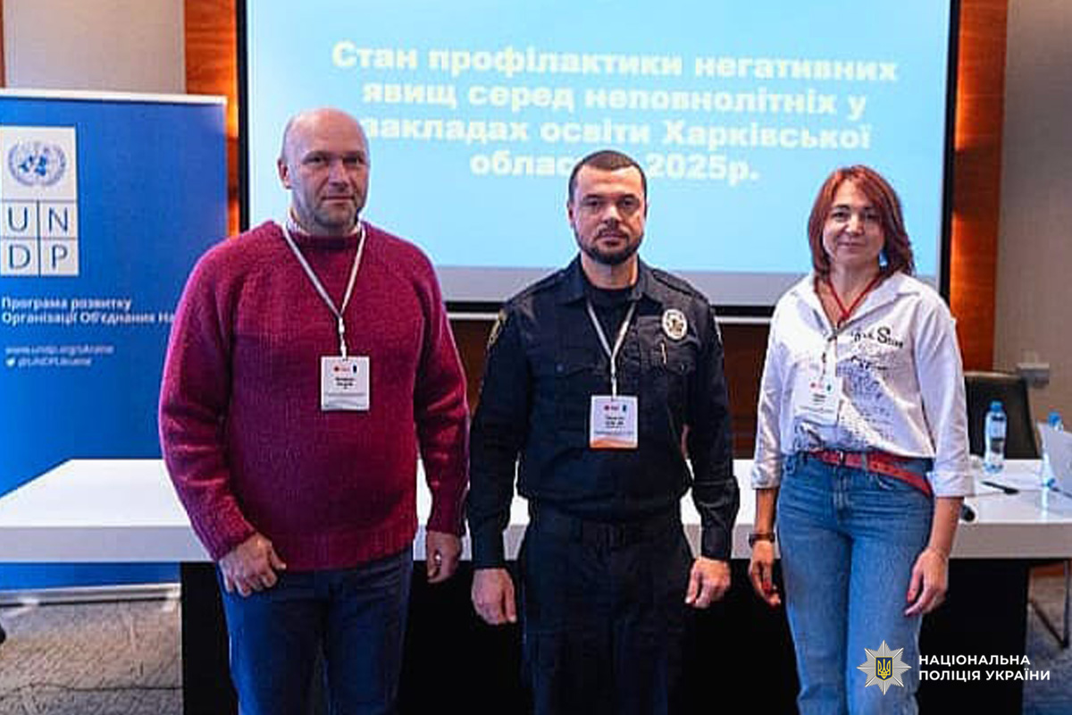 Учасники заходу на тлі екрана презентації та банера; серед них представник поліції.