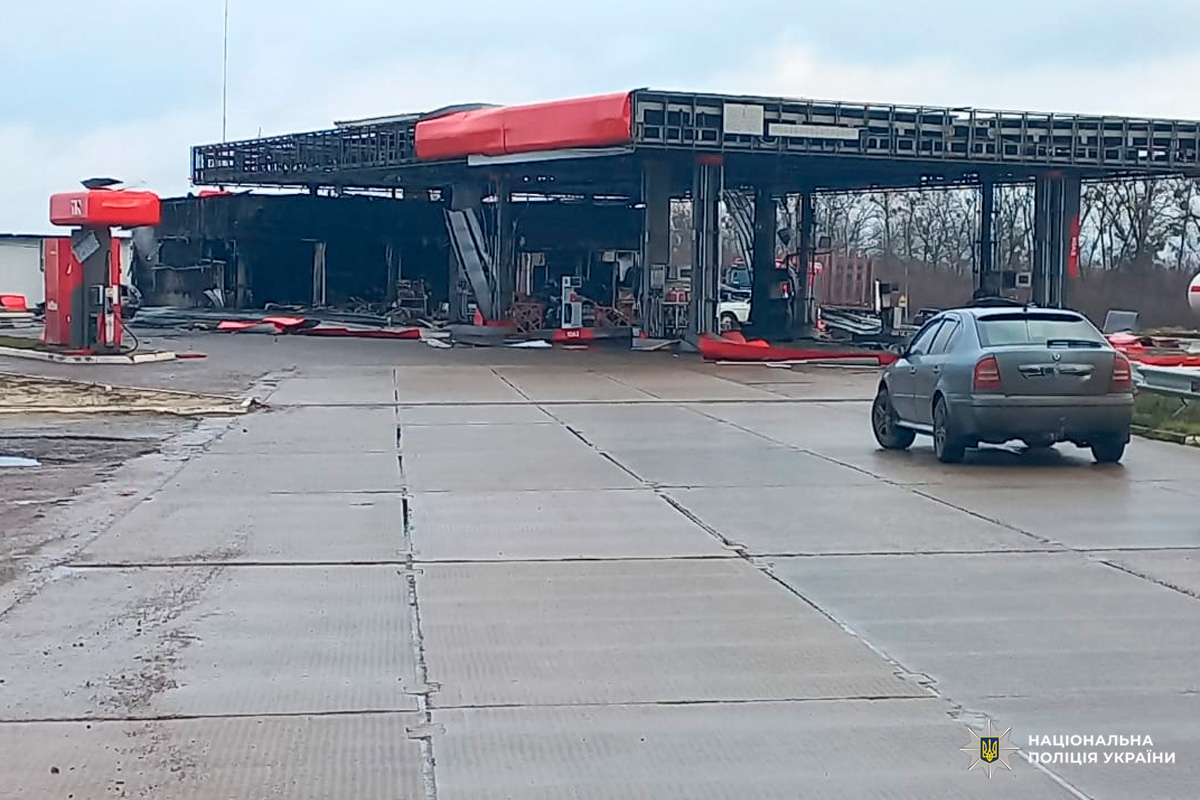 Зруйнована автозаправна станція з обваленим навісом і пошкодженими паливними колонками.