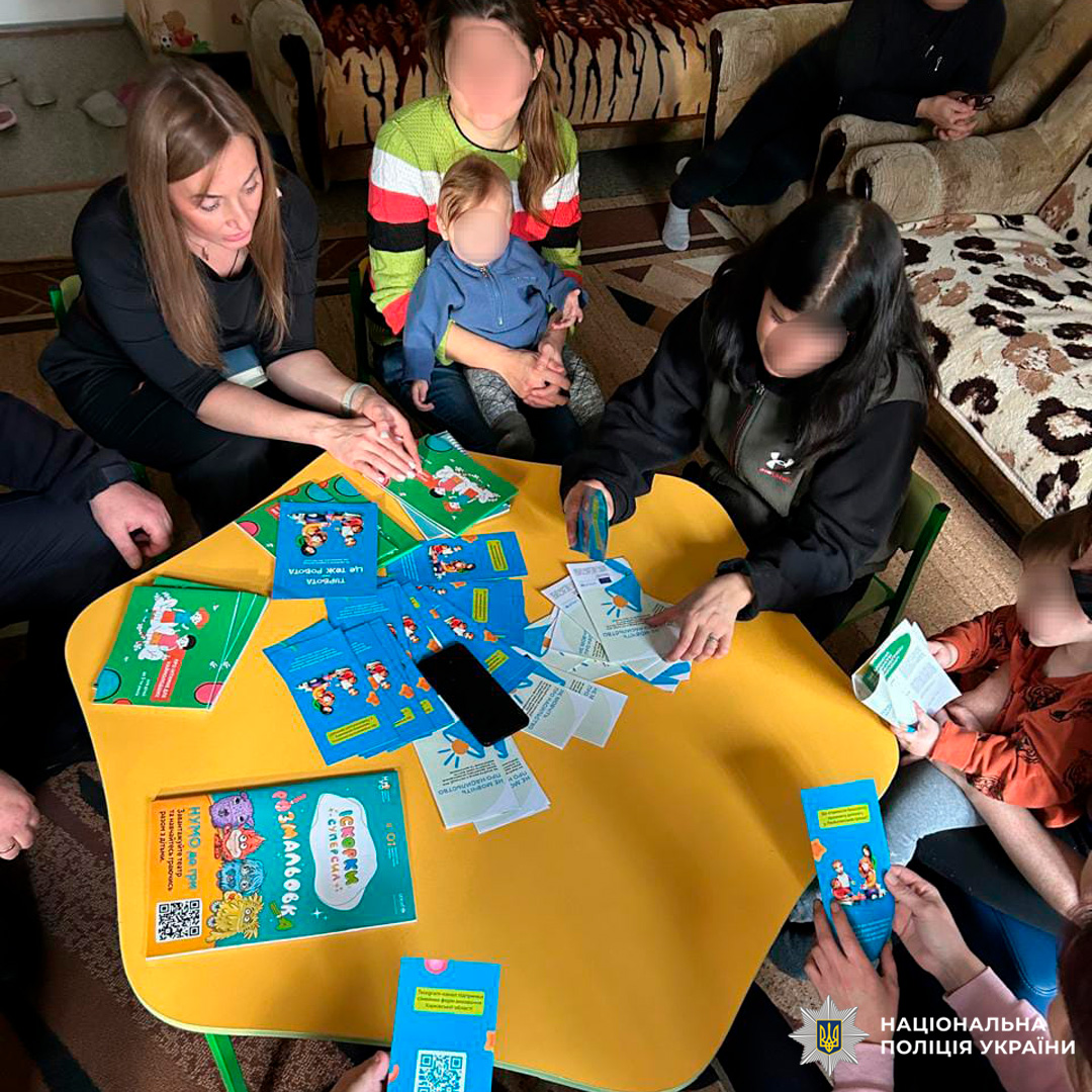 На столі буклети, навколо дорослі та діти.