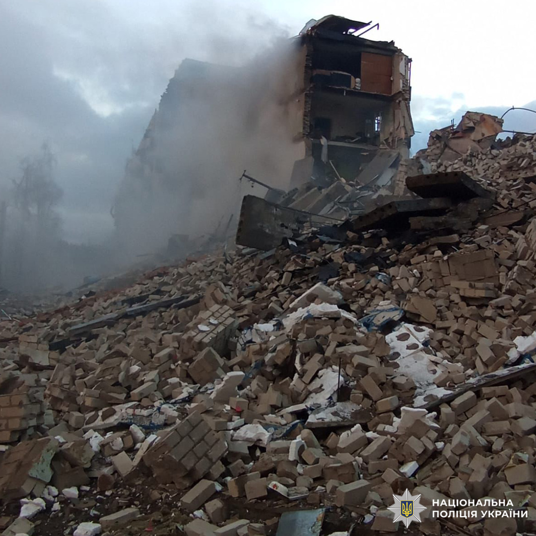 Зруйнована будівля з обваленими конструкціями та димом, що підіймається над уламками.