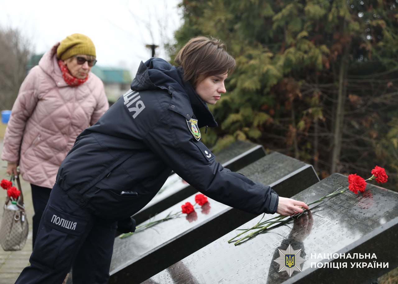 На фото поліцейська кладе квіти до мемореалу.