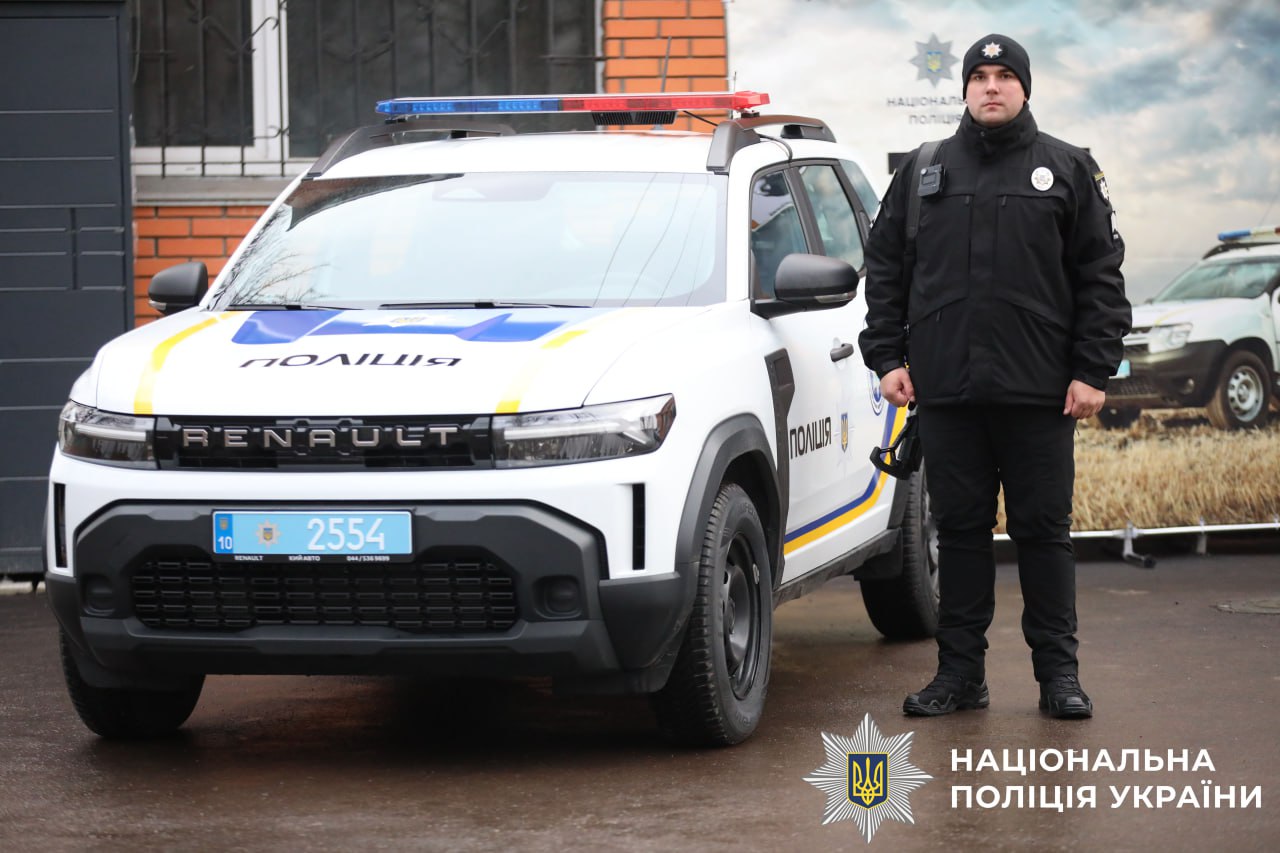 На фото поліцейський офіцер громади біля автомобіля.
