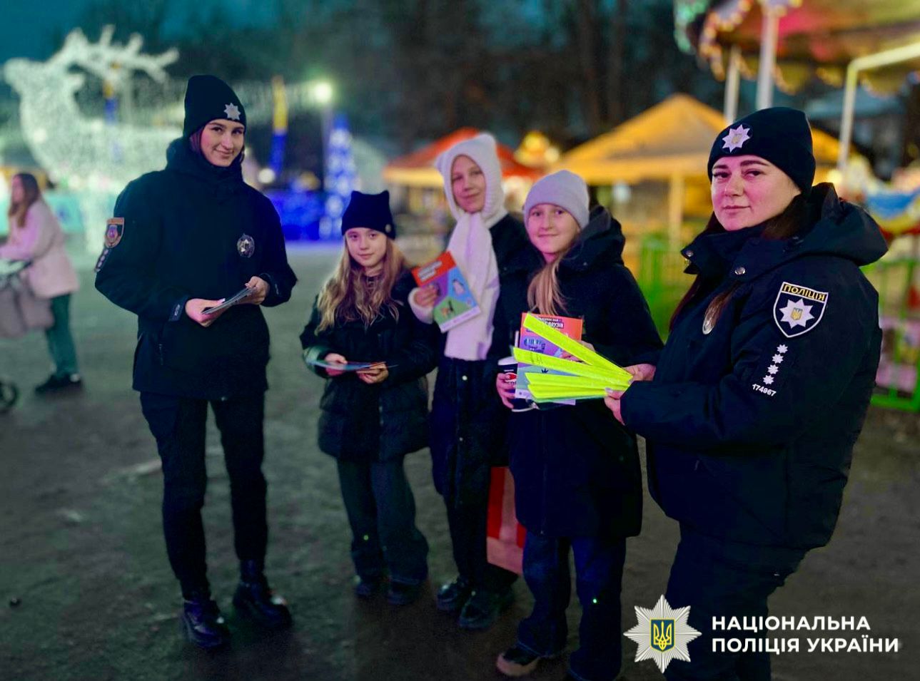На фотографії зображено поліцейських та дітей під час спілкування про обов'язкове носіння світлоповертальних елементів.