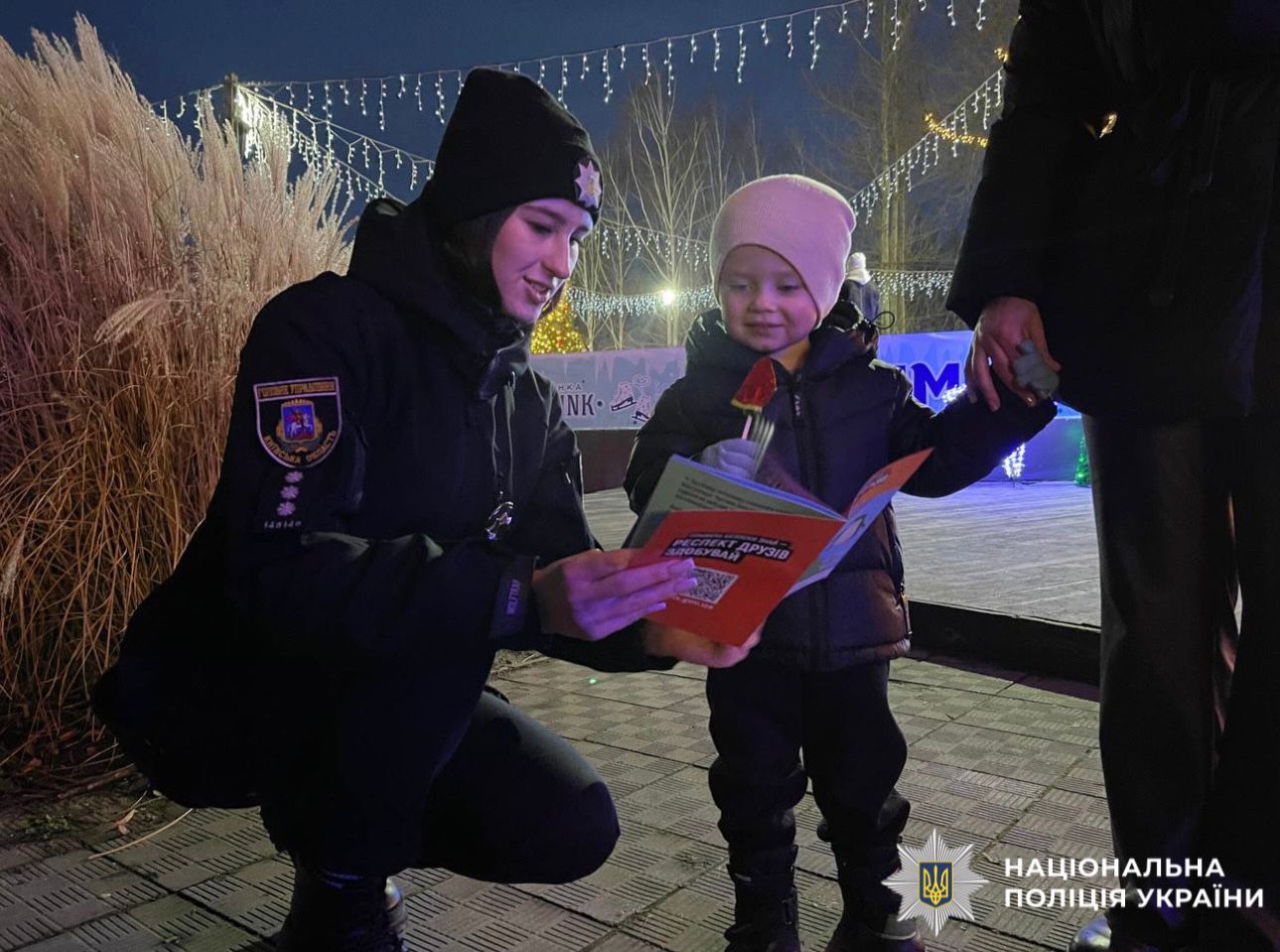На фотографії зображено поліцейську та дитину під час спілкування про обов'язкове носіння світлоповертальних елементів.