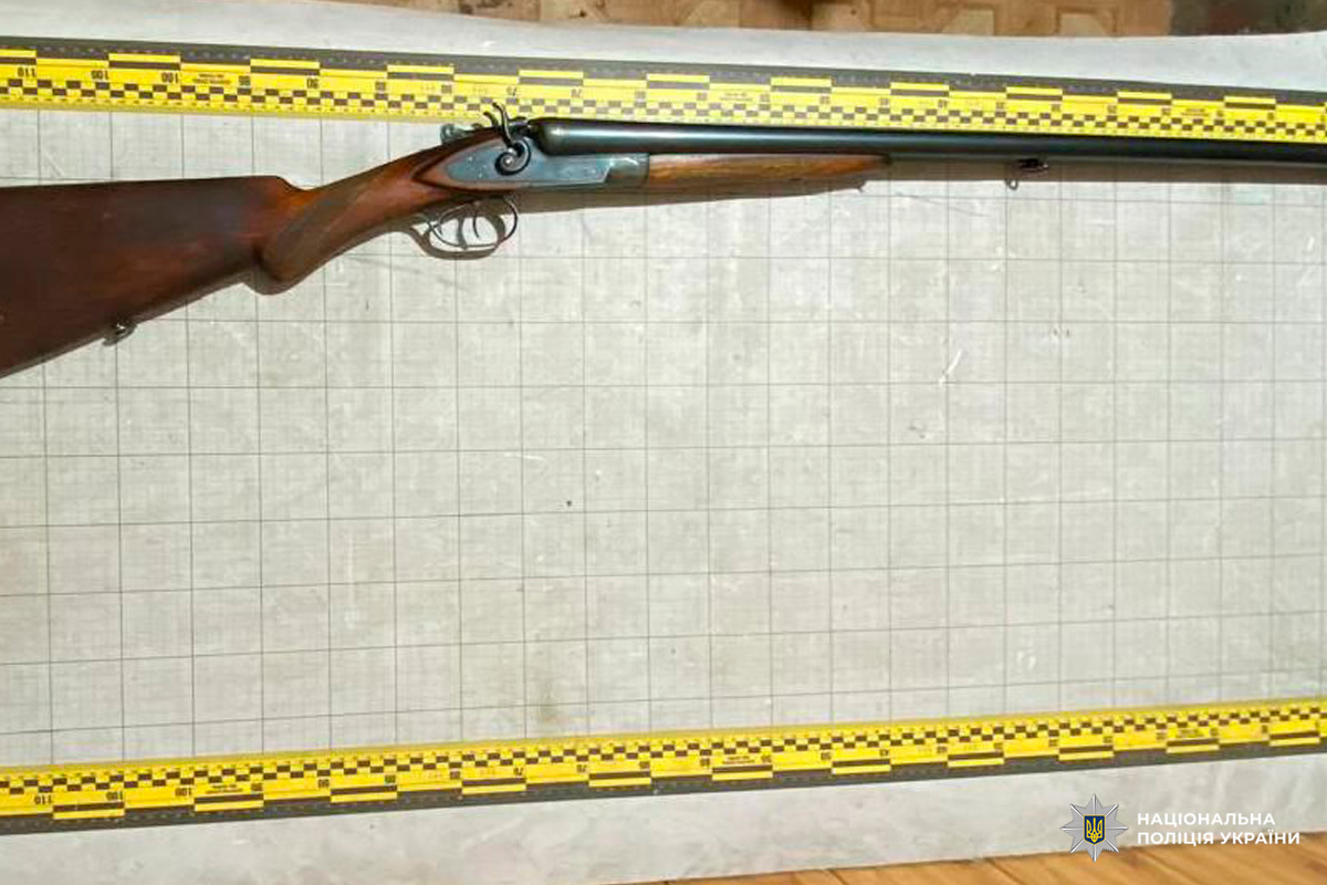 Двоствольна гладкоствольна рушниця з дерев’яним прикладом, розміщена на фоні з вимірювальною сіткою та шкалами зверху і знизу.