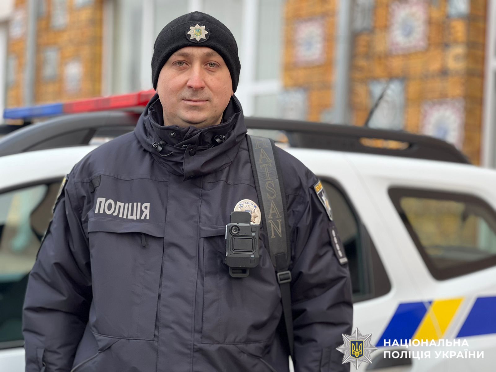 На фото зображений працівник поліції біля службового авто