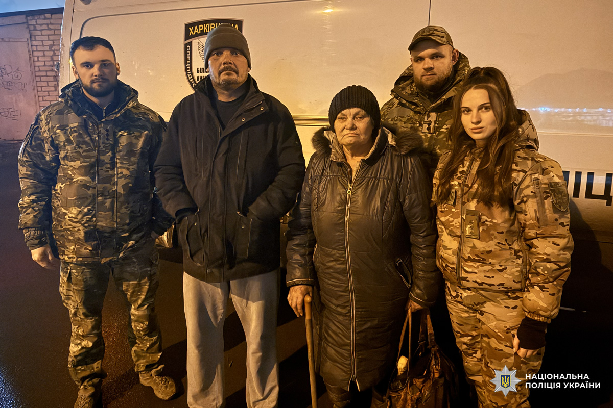 Поліцейські та цивільні біля білого мікроавтобуса.