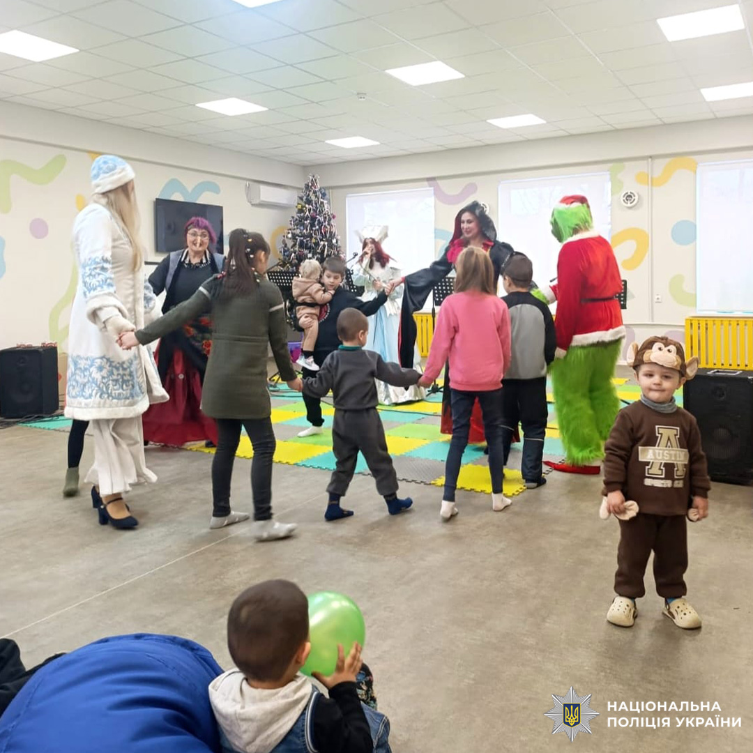 Діти та дорослі беруть участь у святковій грі біля ялинки.