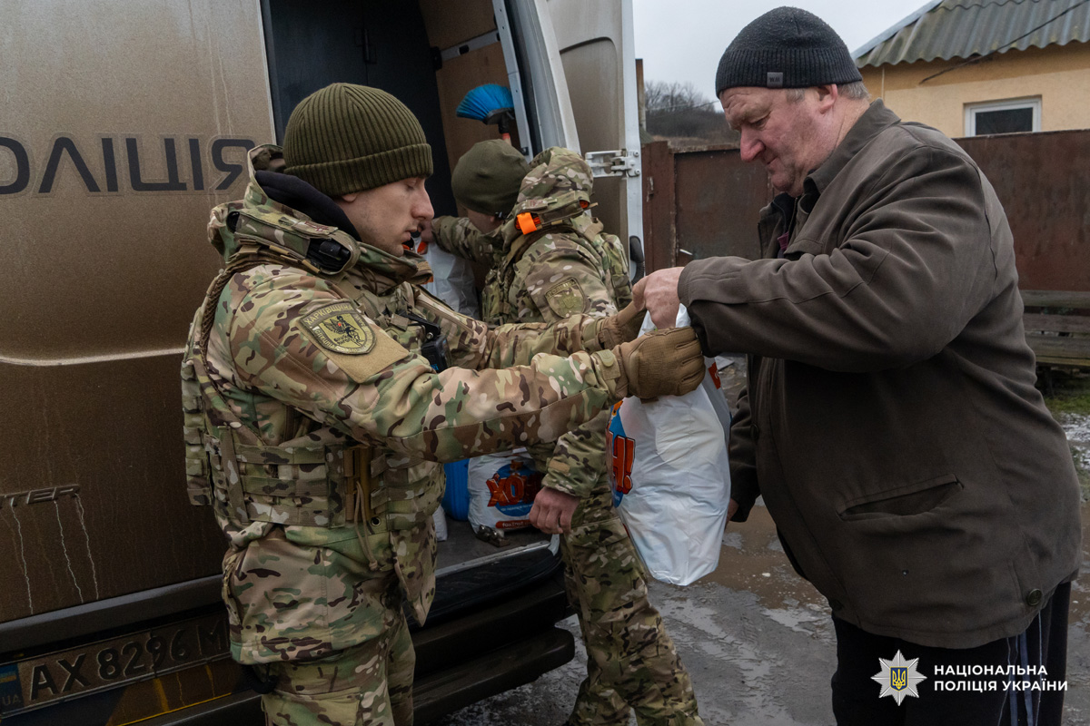 Поліцейські у камуфляжній формі передають пакети допомоги цивільному.