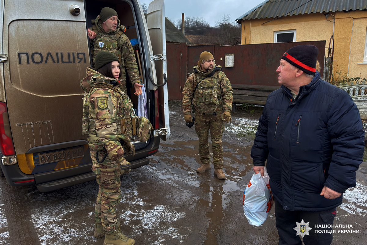 Поліцейські у камуфляжній формі передають пакети допомоги цивільному.