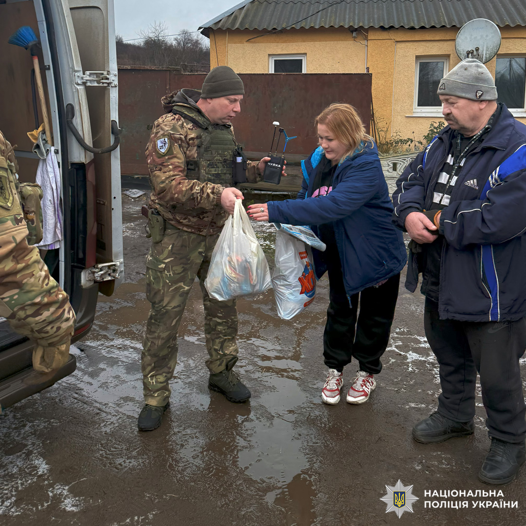 Поліцейські у камуфляжній формі передають пакети допомоги цивільному.