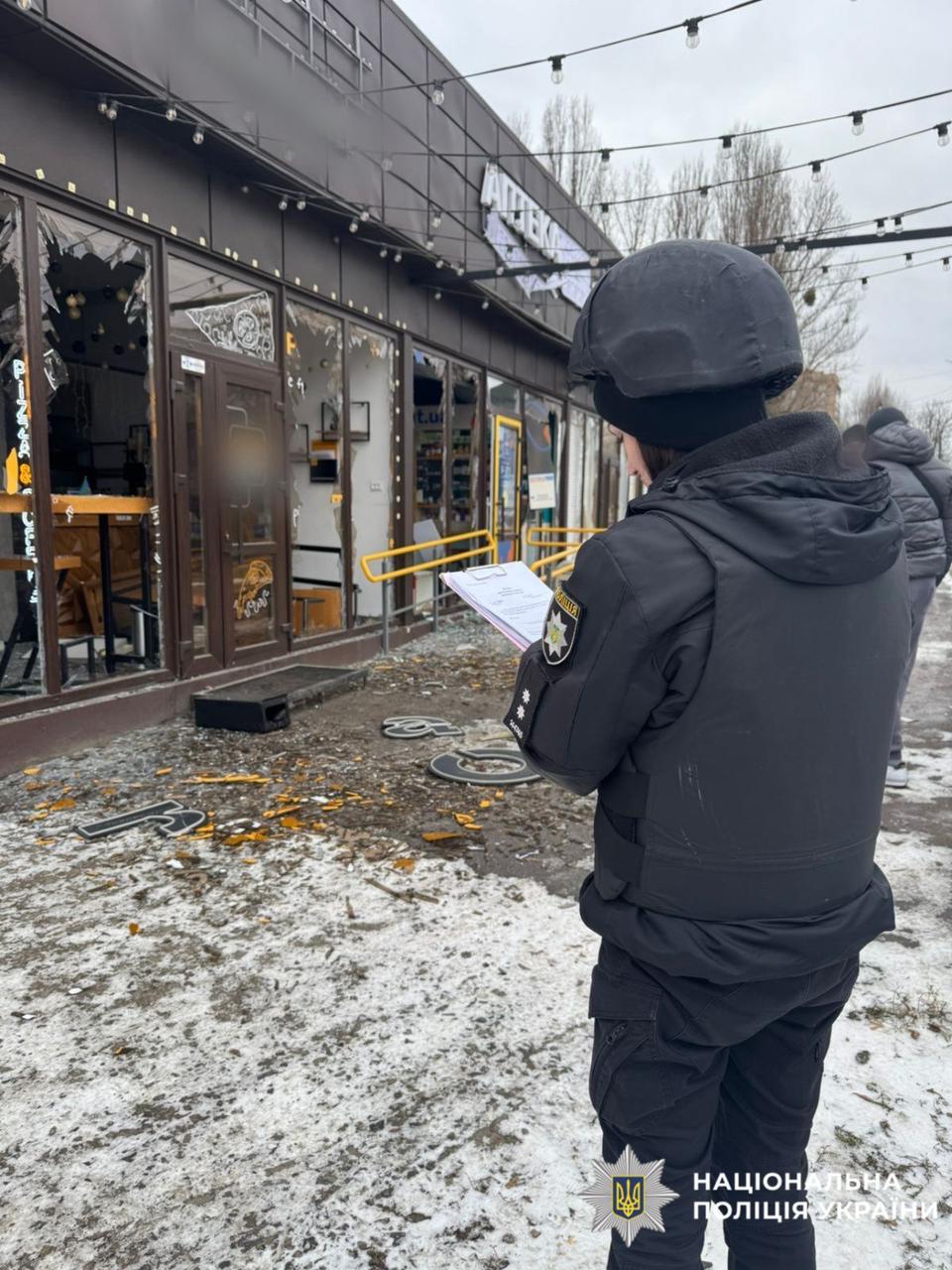 На фото пошкоджена будівля, внаслідок атаки. Працівник поліції працює на місці події.