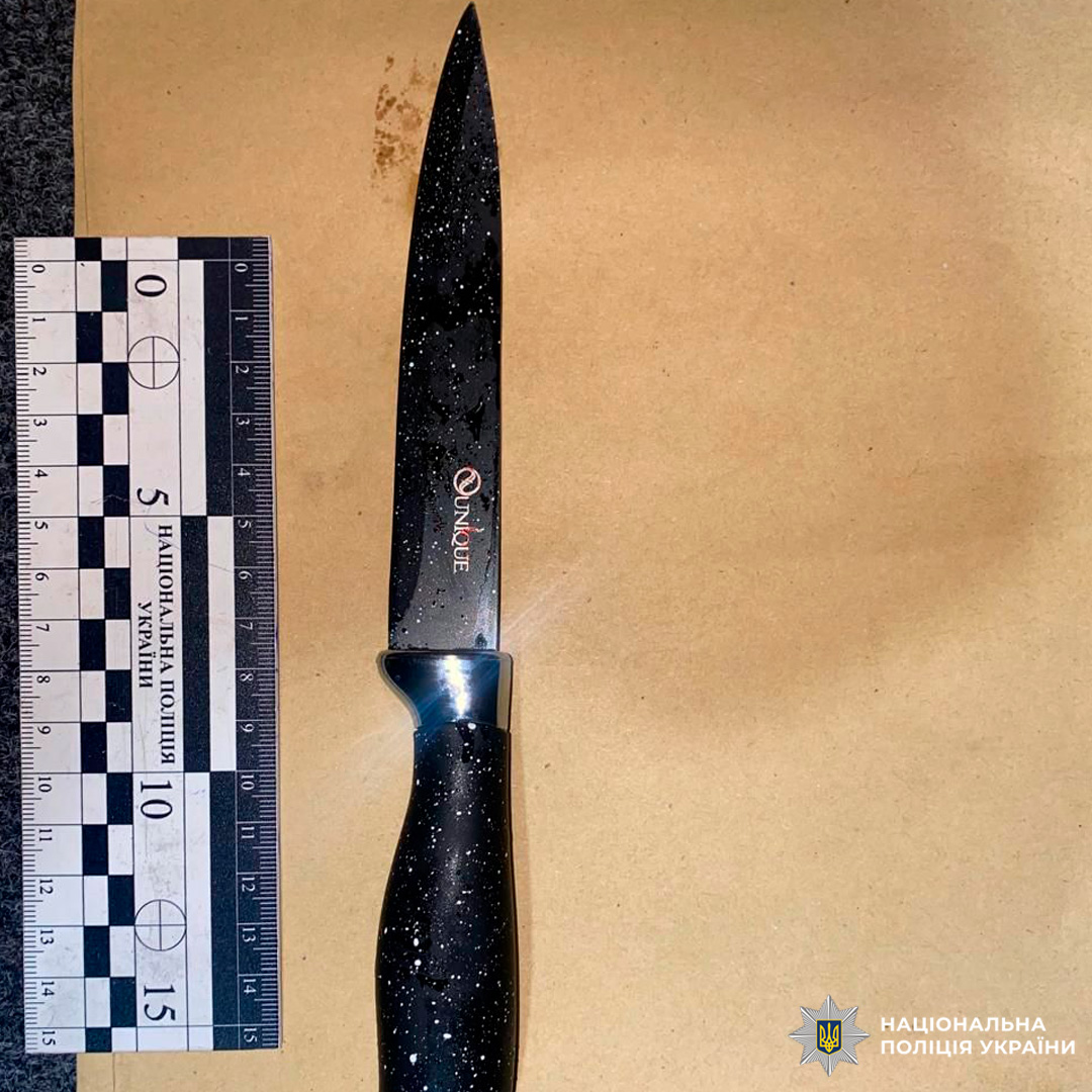 Чорний кухонний ніж із білими крапками поруч із вимірювальною шкалою.