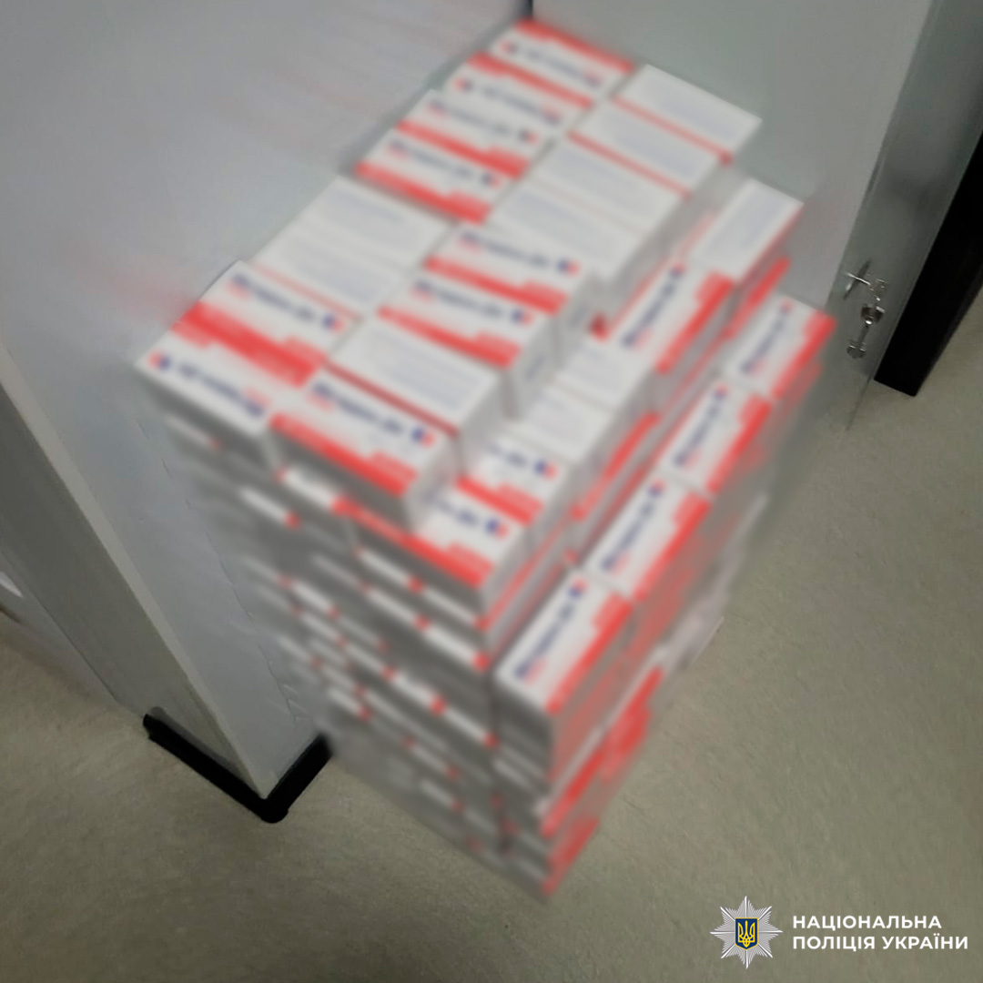 Численні коробки препарату, складені у стопку біля стіни.