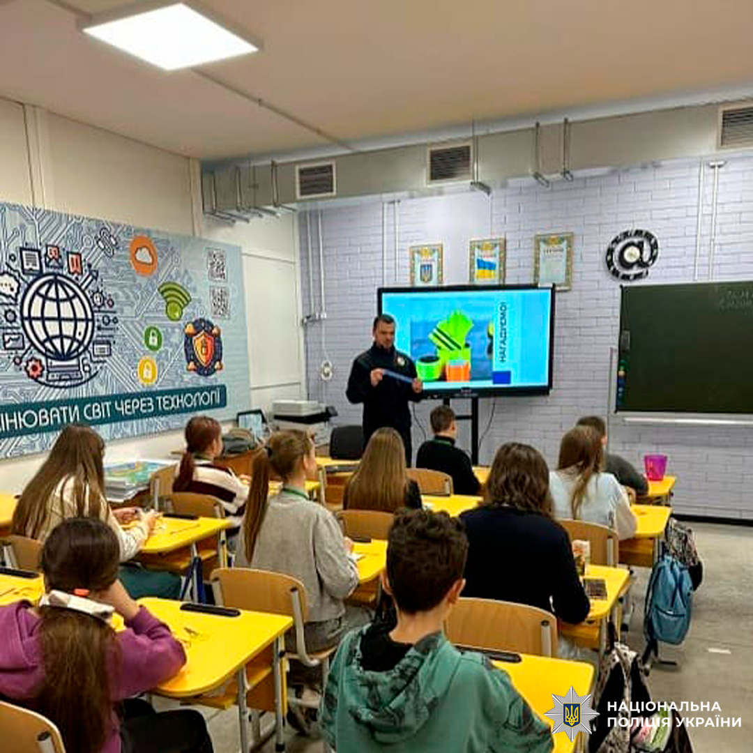 Учні слухають лекцію представника Національної поліції України у сучасному класі з цифровим екраном.