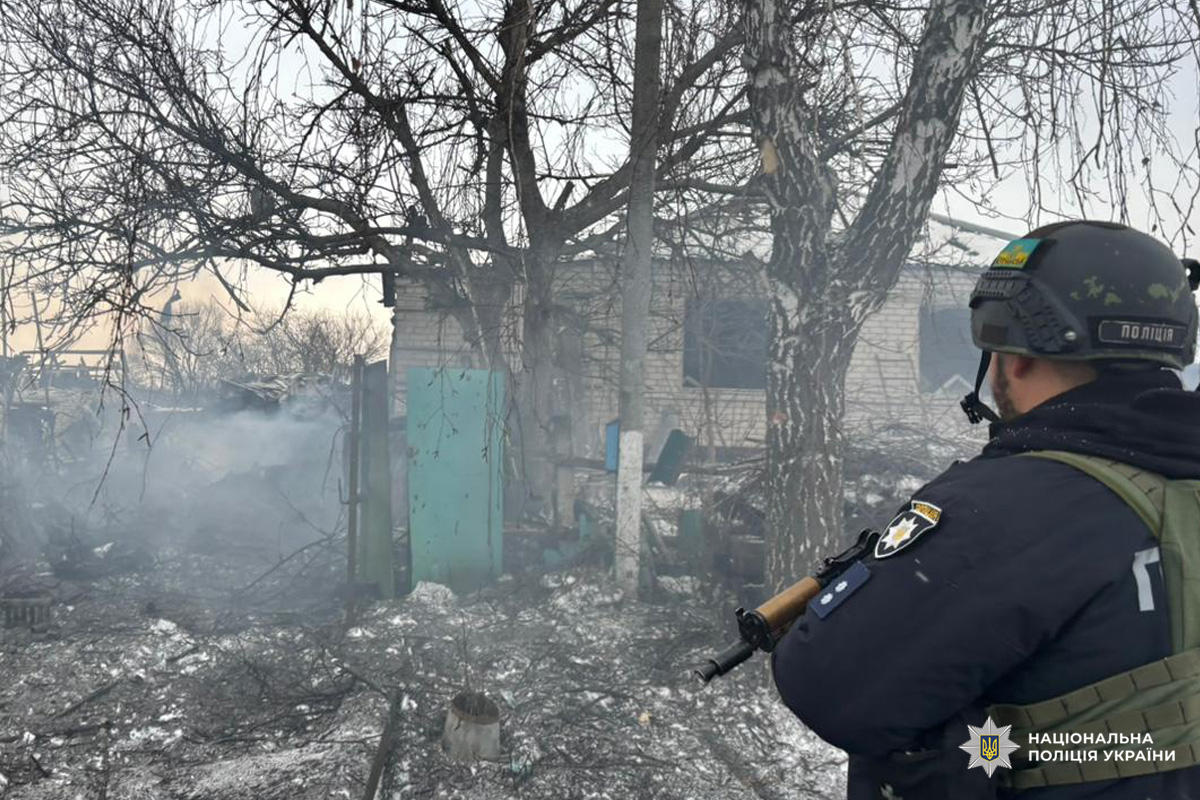 Поліцейський у спорядженні біля зруйнованої будівлі взимку.