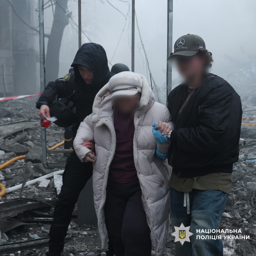 Поліцейські евакуюють літню людину з місця руйнувань.