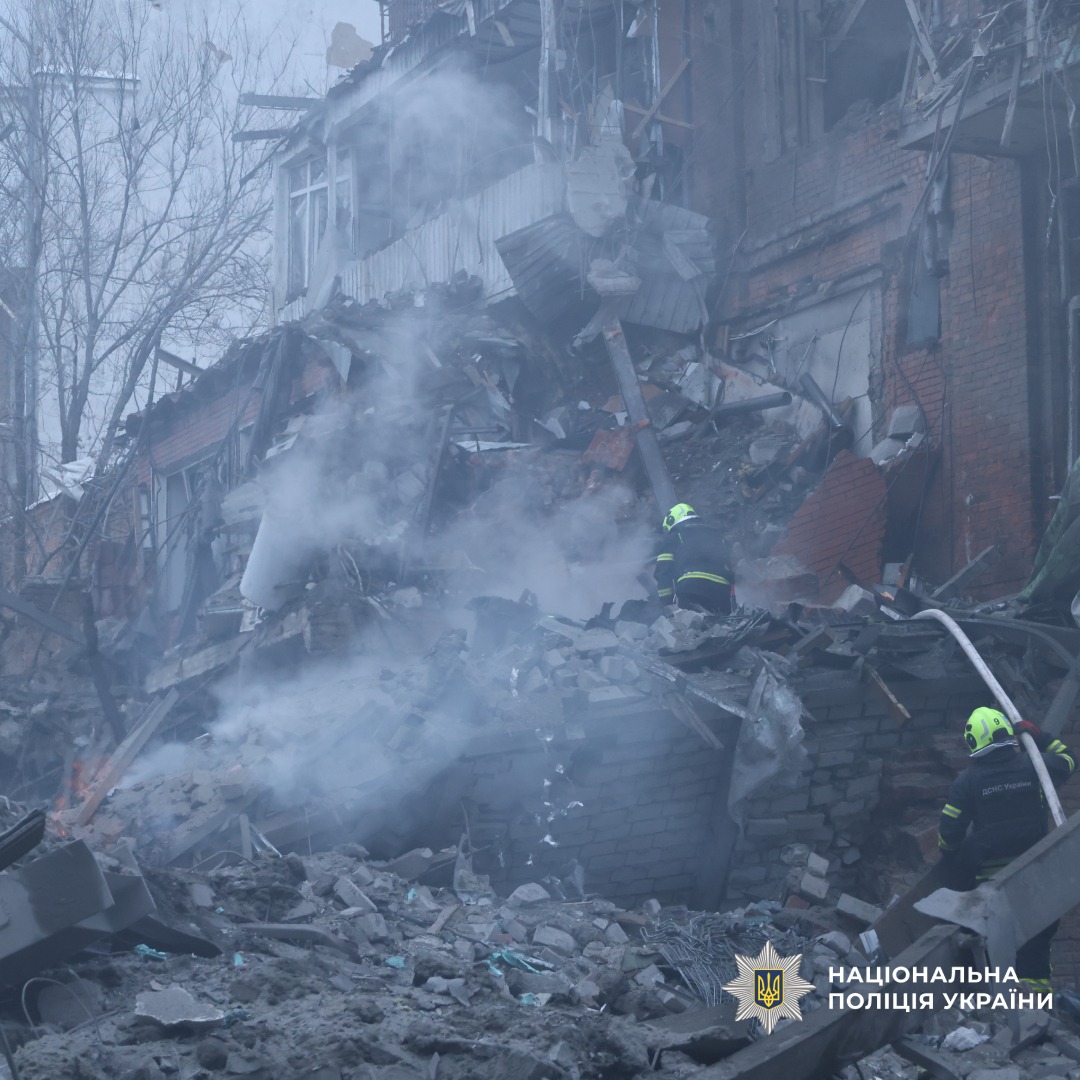 Зруйнована будівля з обваленими стінами та димом.