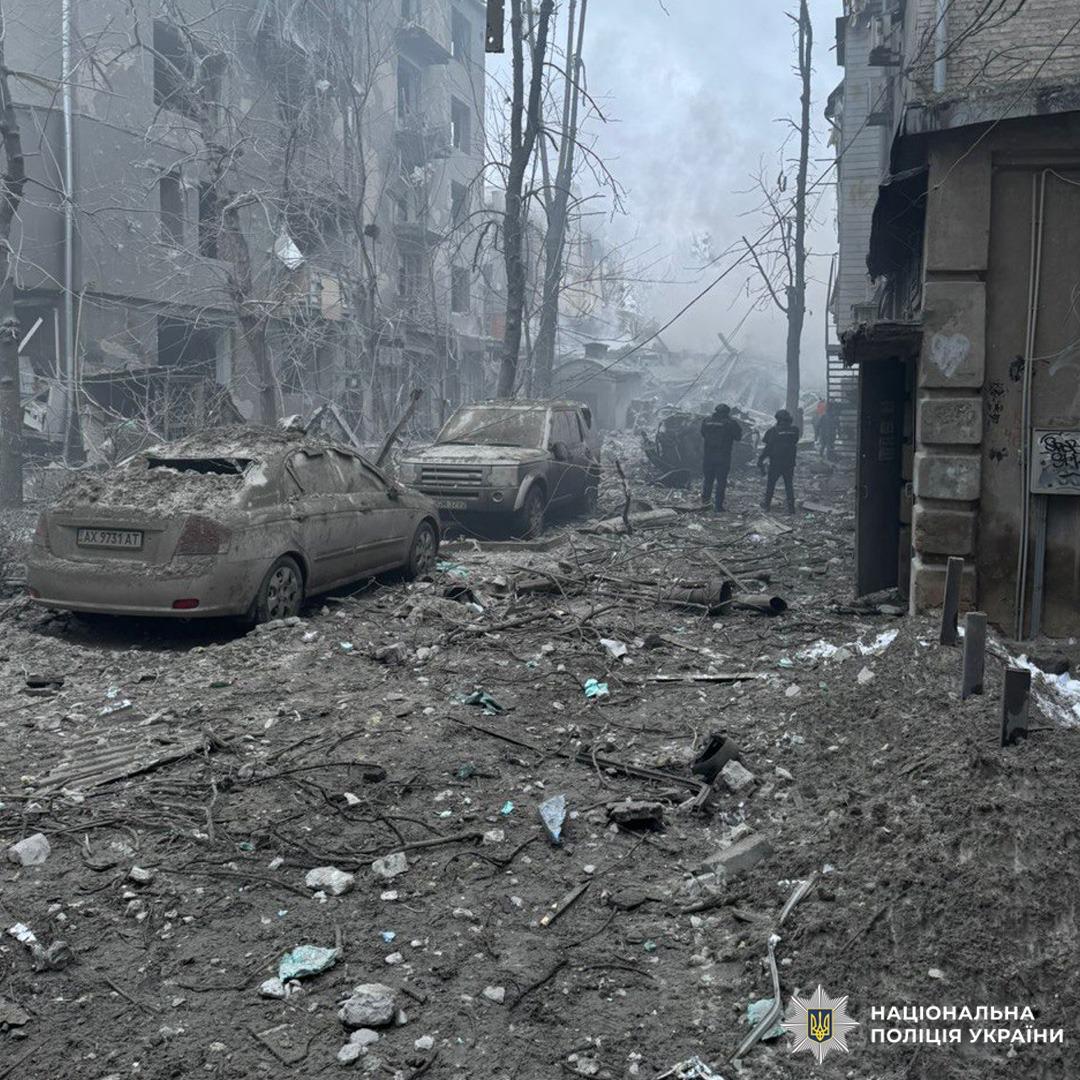 Зруйнована вулиця з уламками та пошкодженими автомобілями.