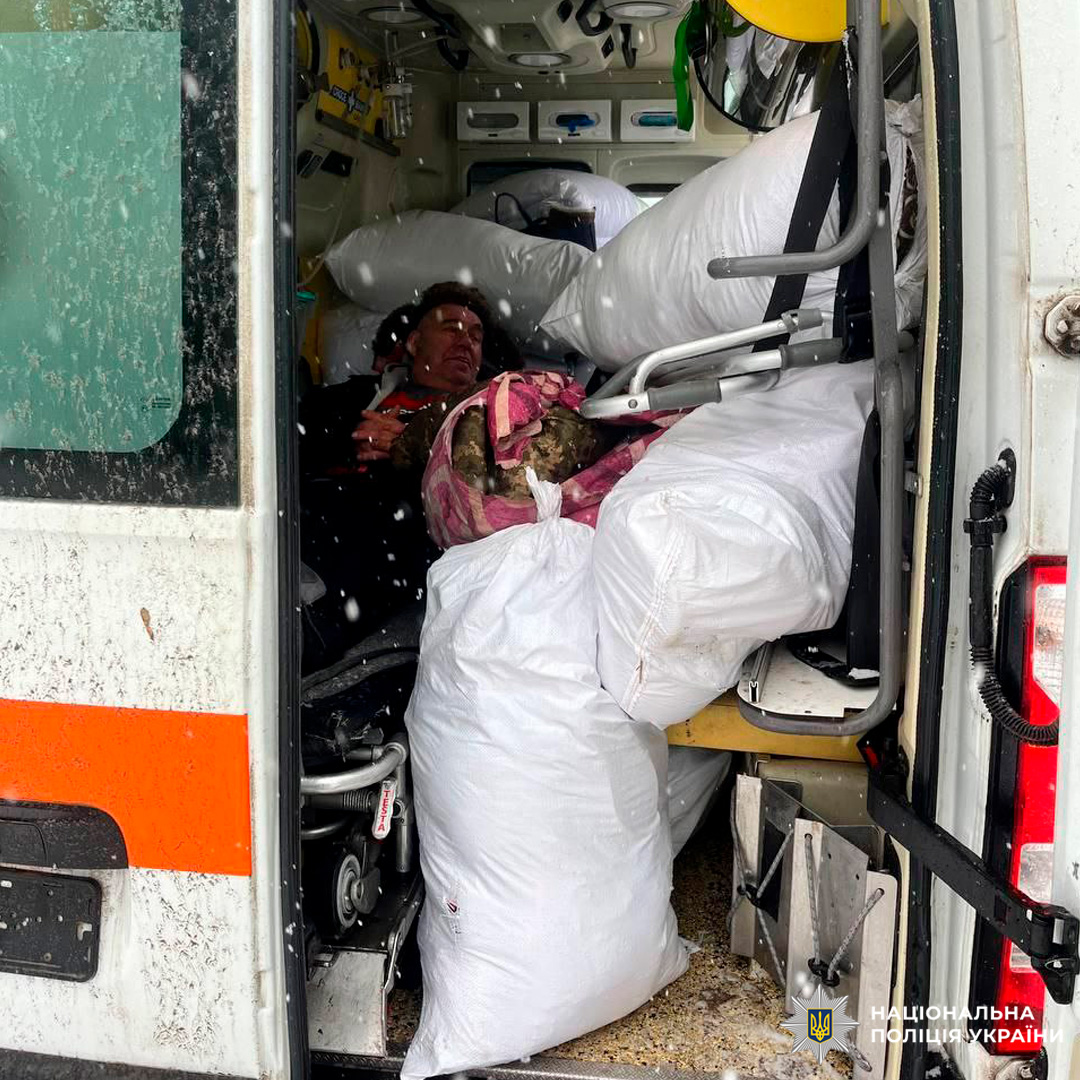 Літній чоловік  сидить у мікроавтобусі серед білих мішків.