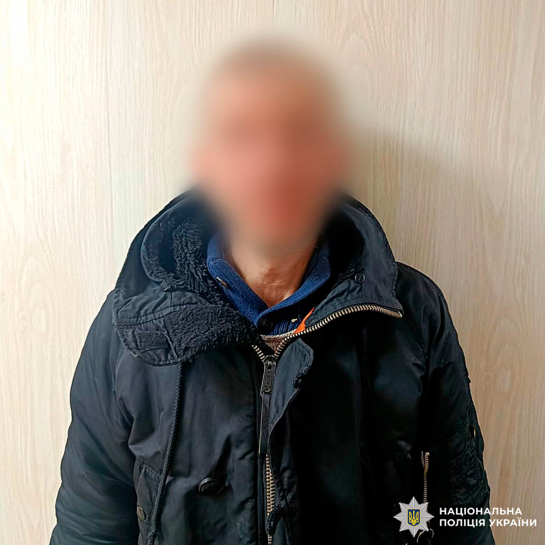 Особа у зимовому одязі стоїть біля світлої дерев’яної стіни, обличчя розмите з міркувань конфіденційності.