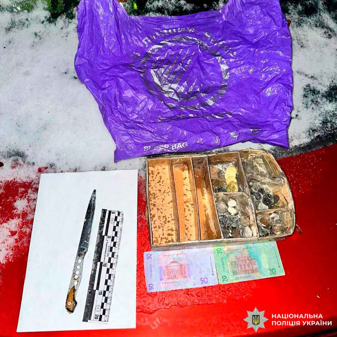 Поліція України документує вилучені речові докази: ніж, гроші та інші предмети на снігу.