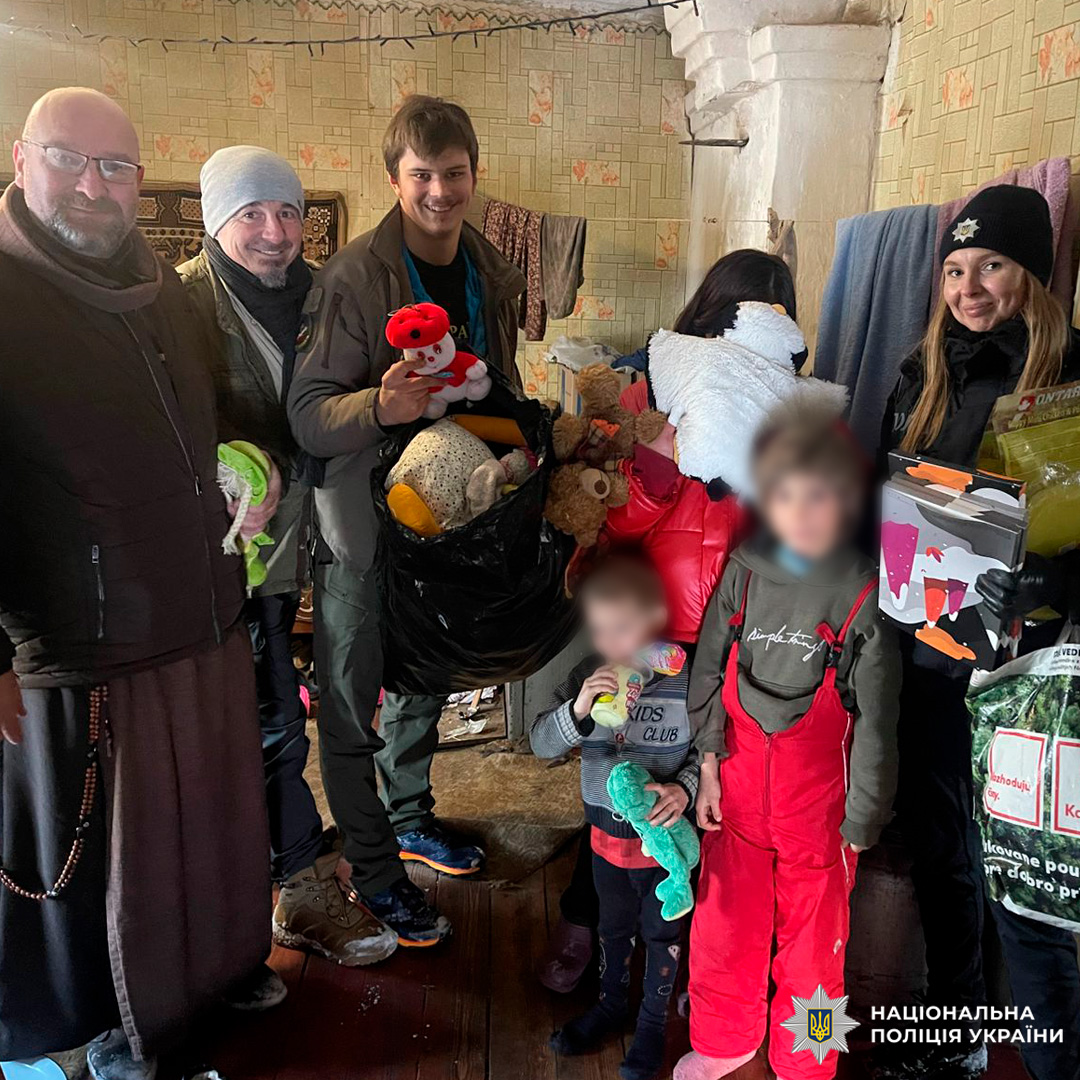 Дорослі та діти з подарунками й іграшками в кімнаті.