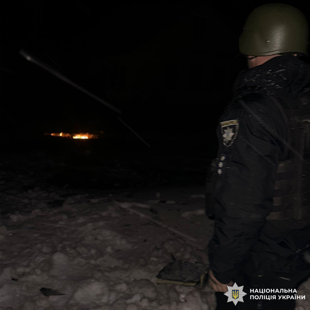 Поліцейський у спорядженні стоїть біля вогню серед снігу.