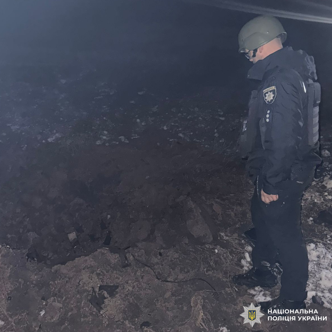 Поліцейський у спорядженні оглядає вирву вночі.