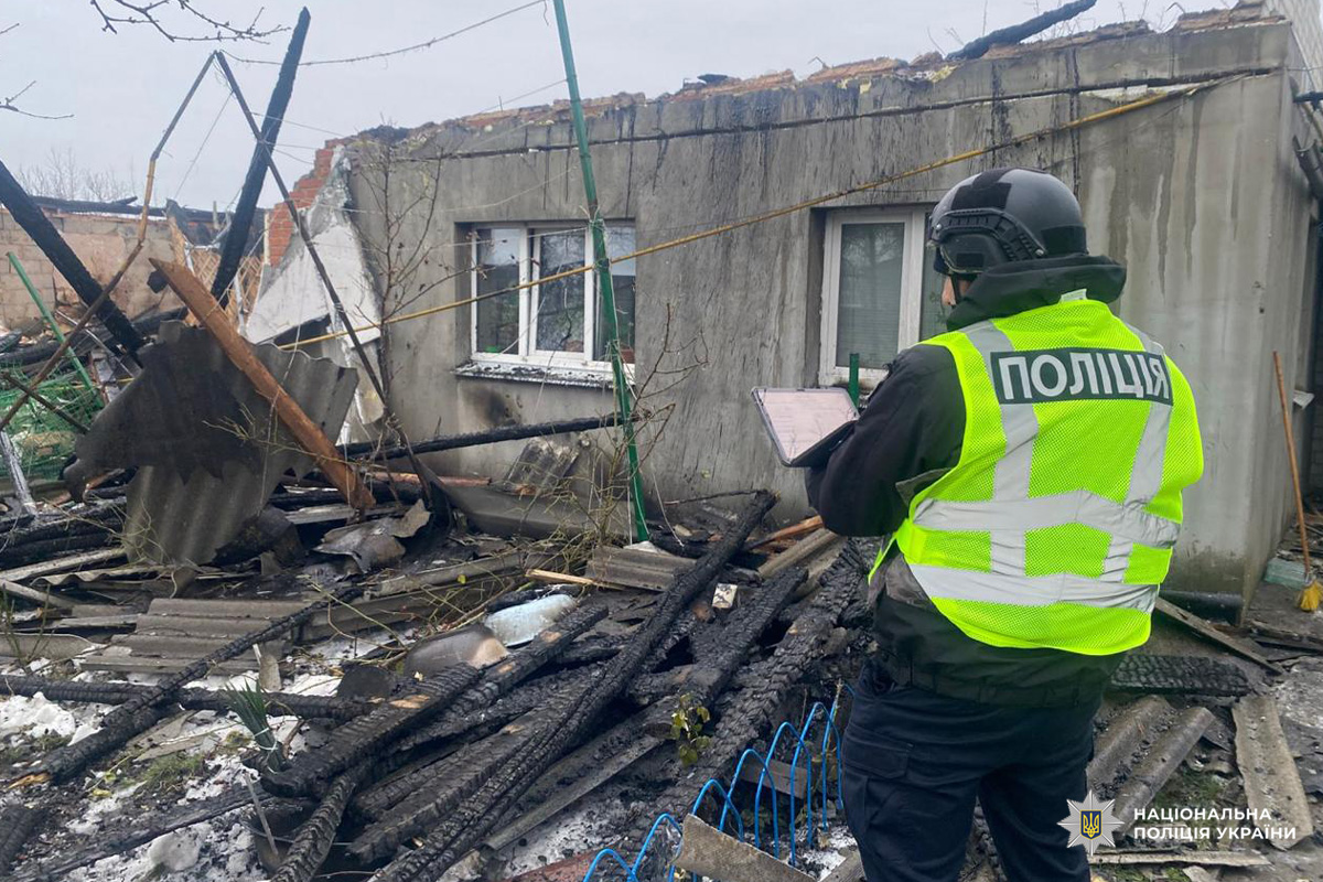 Поліцейський у жилеті документує руйнування будівлі.