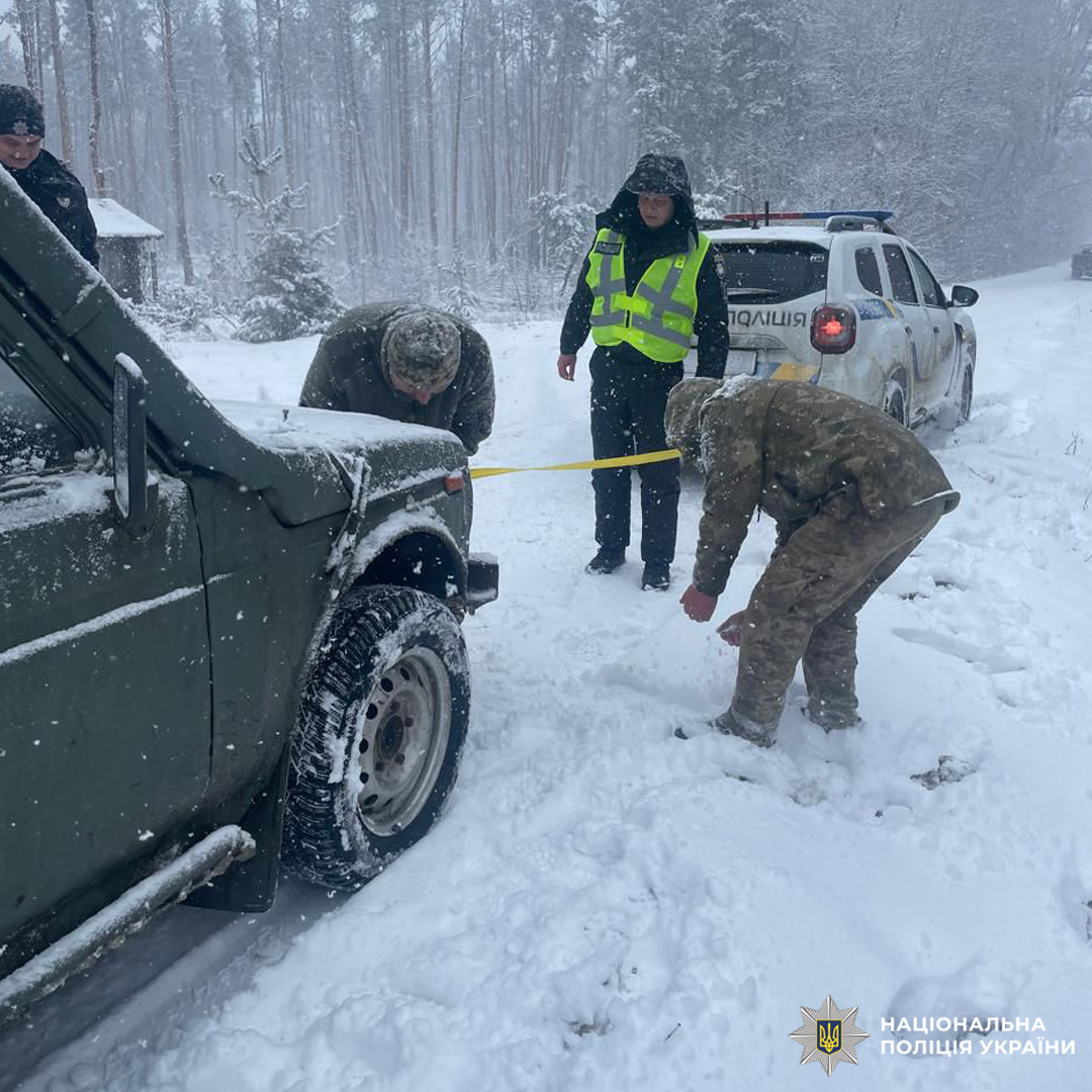 Поліцейські допомагають витягнути авто зі снігу.