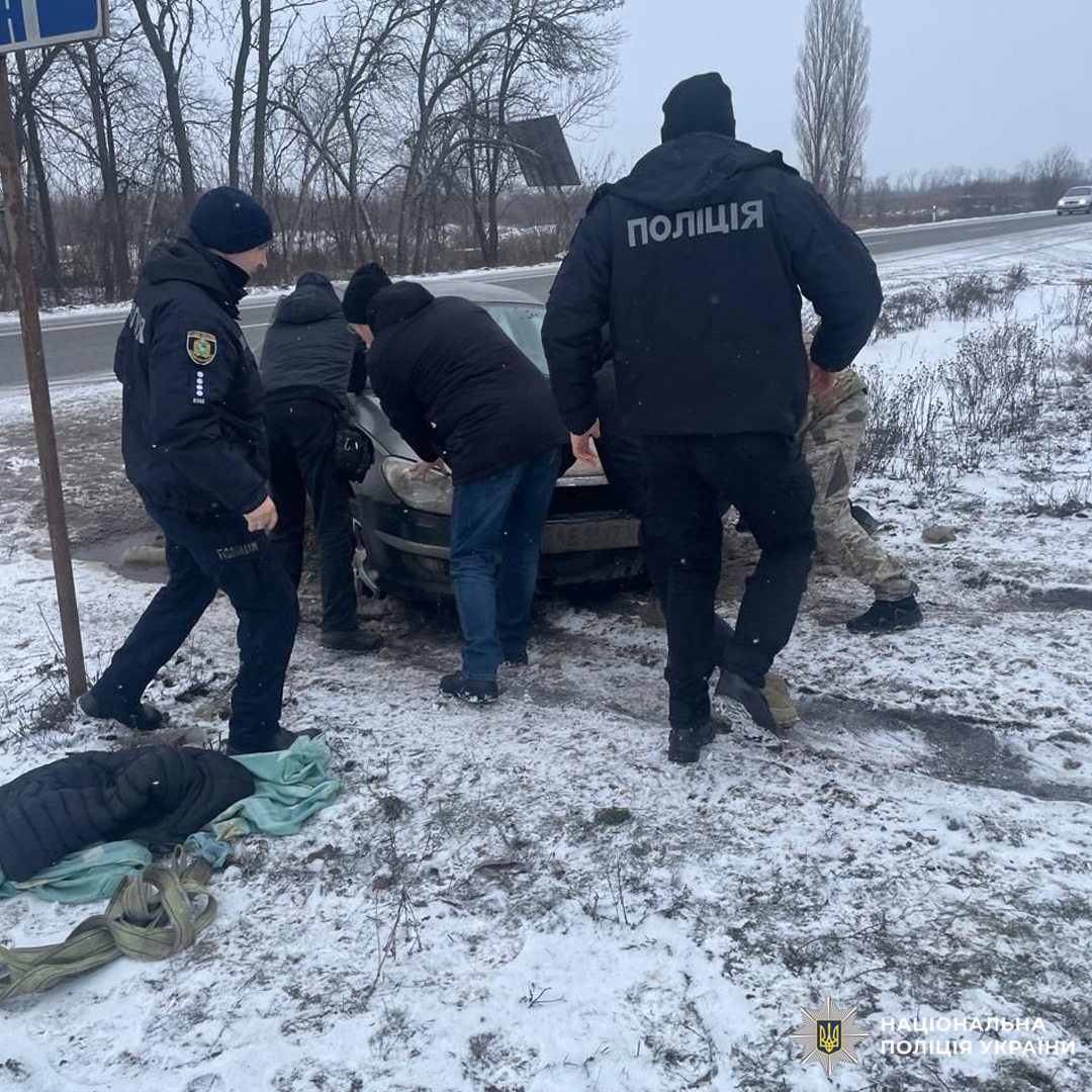 Поліцейські допомагають витягнути авто зі снігу.