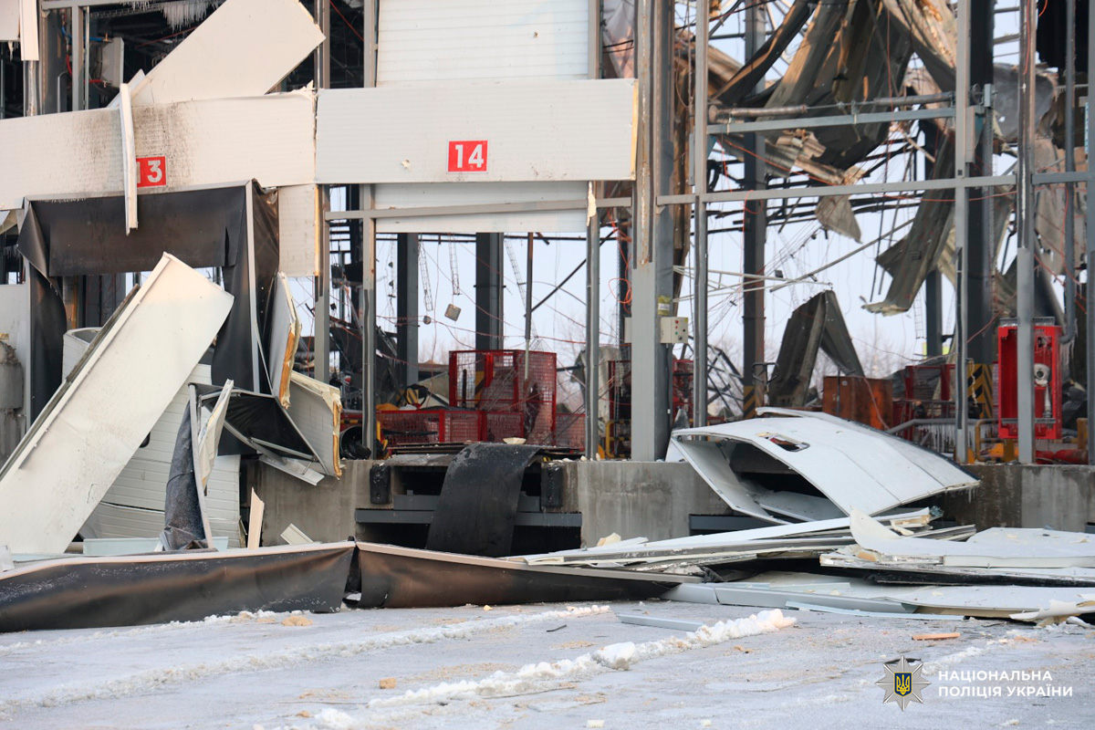 Зруйнована металева конструкція з обваленим дахом та уламками на землі.