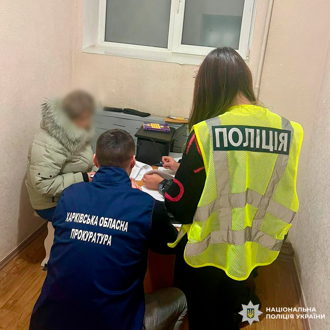 Поліцейський та представник прокуратури проводять опитування жінки у службовому приміщенні.