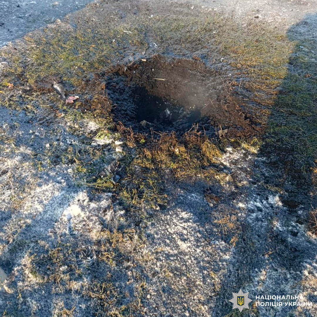 Кратер у землі після вибуху, вкритий снігом та уламками.