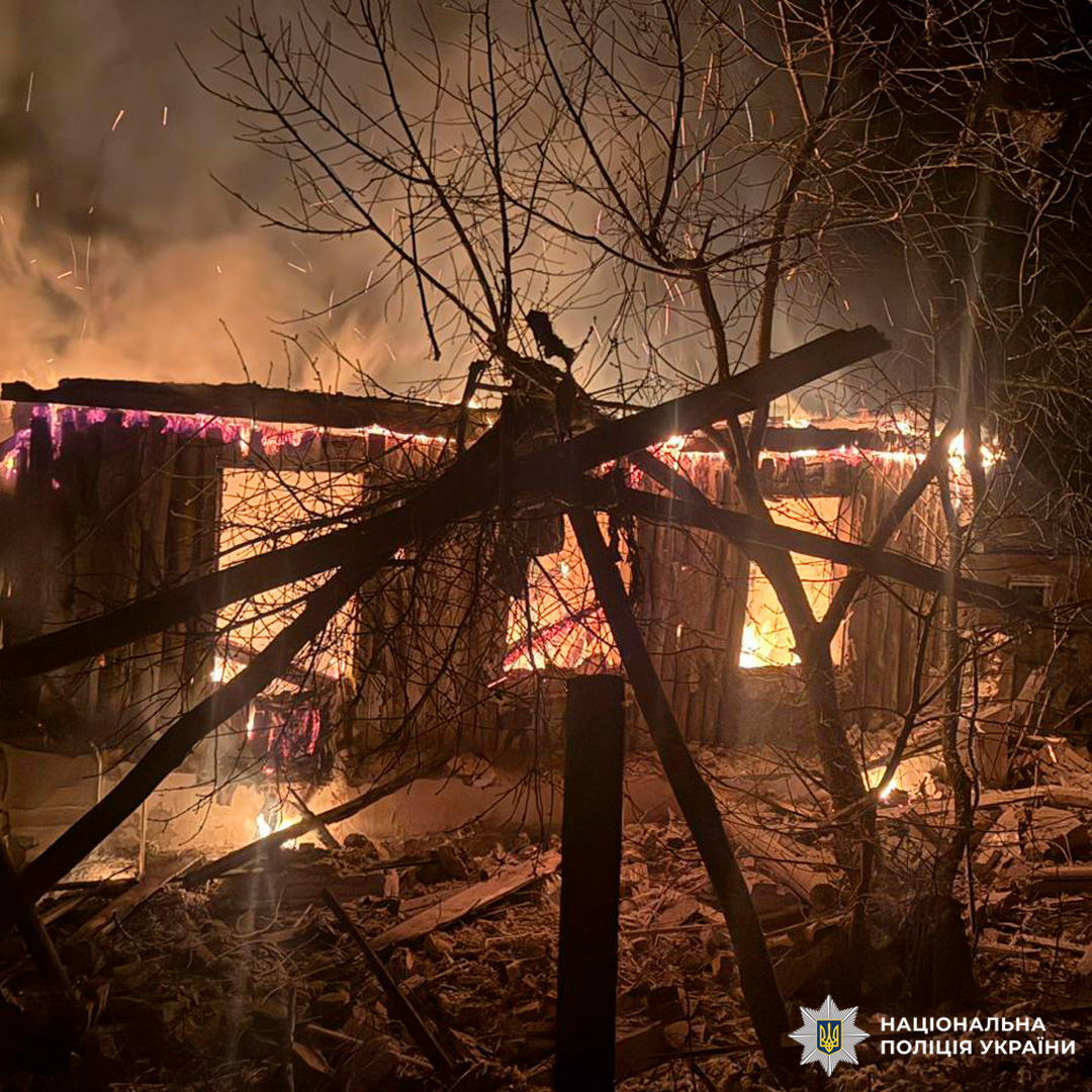 Дерев’яна будівля у вогні вночі, сильне полум’я та дим.