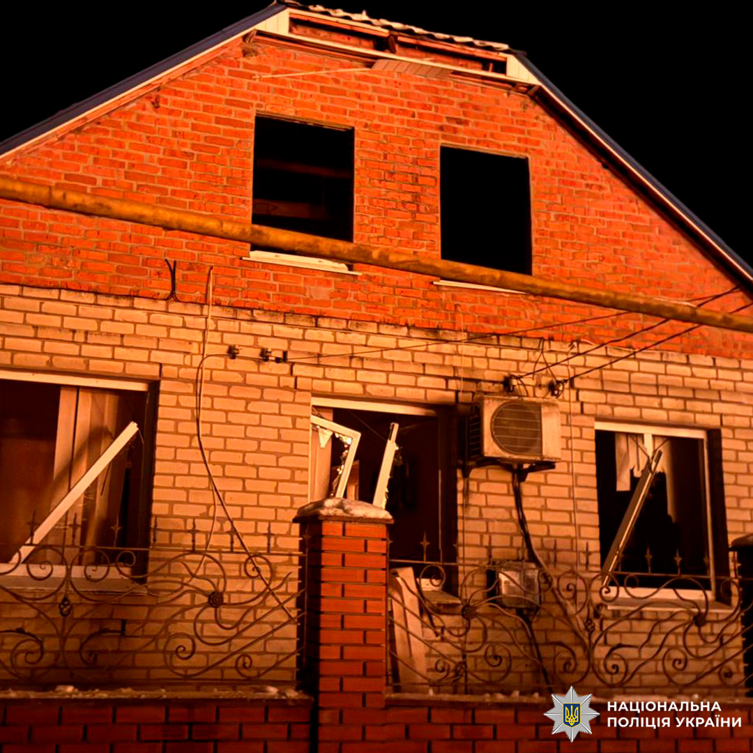Пошкоджений цегляний будинок уночі з вибитими вікнами.