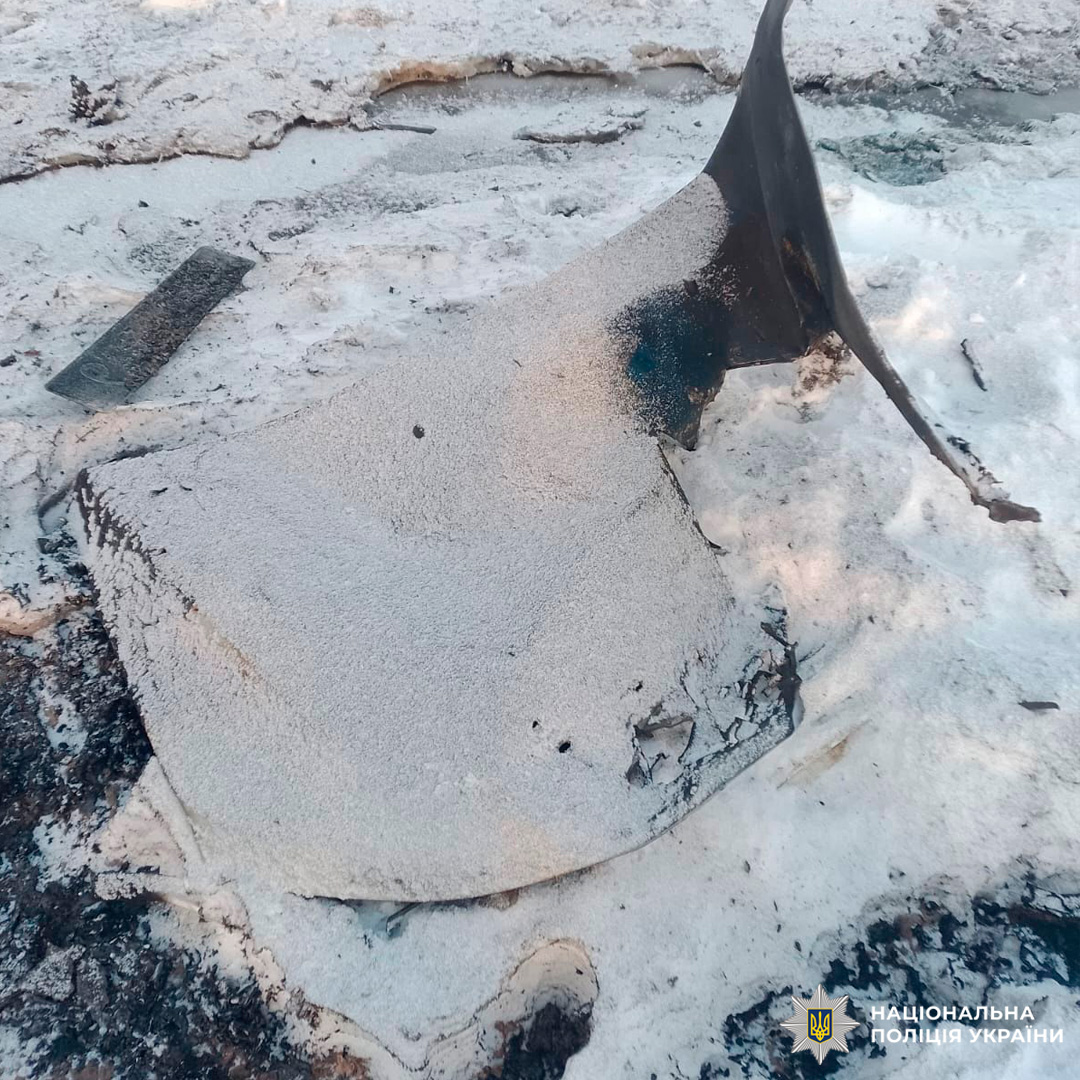 Великий обгорілий уламок металу на засніженій землі.