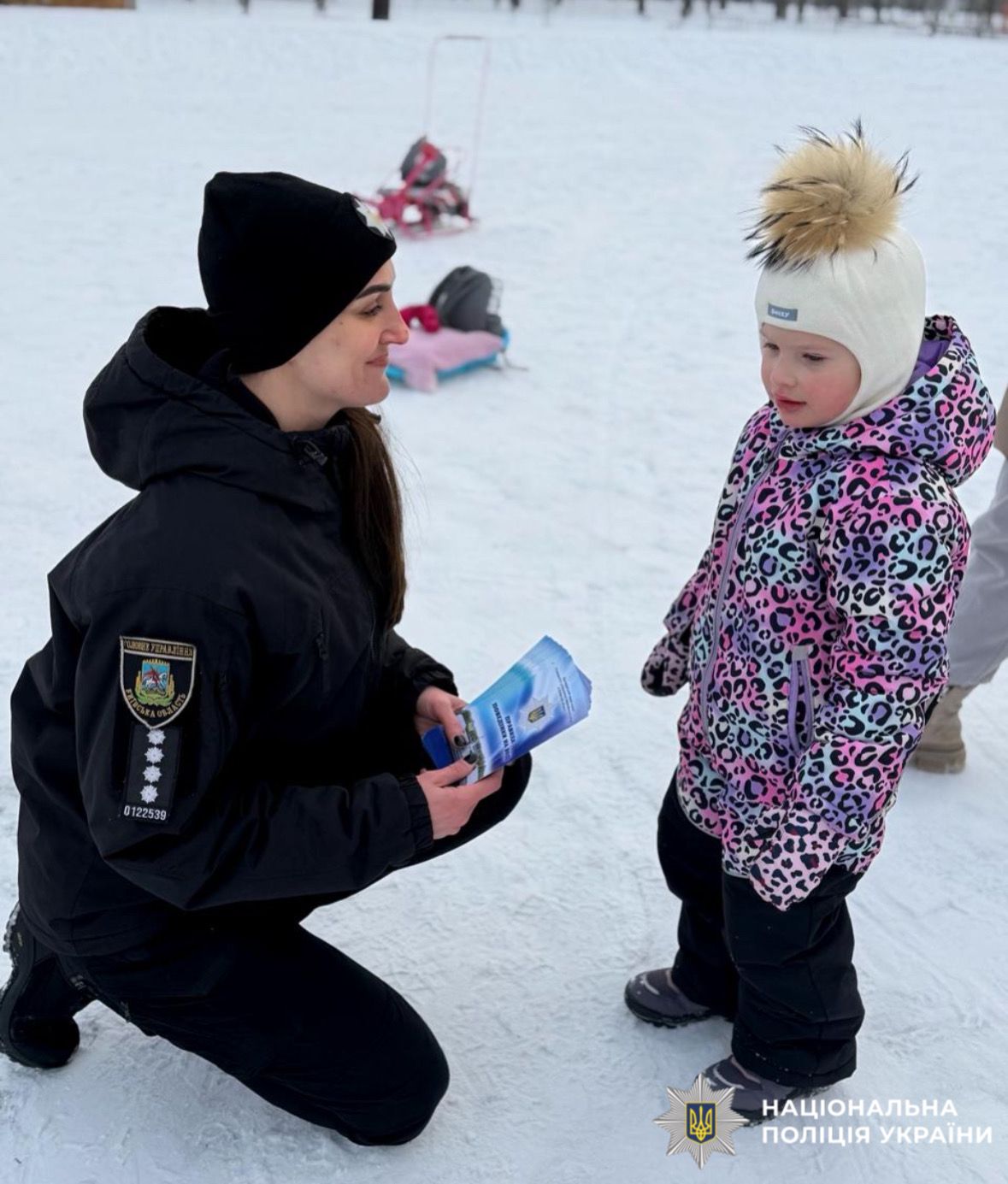На фотографії зображено ювенальну поліцейську, яка проводить профілактичний захід з дітьми поблизу зимових водойм.