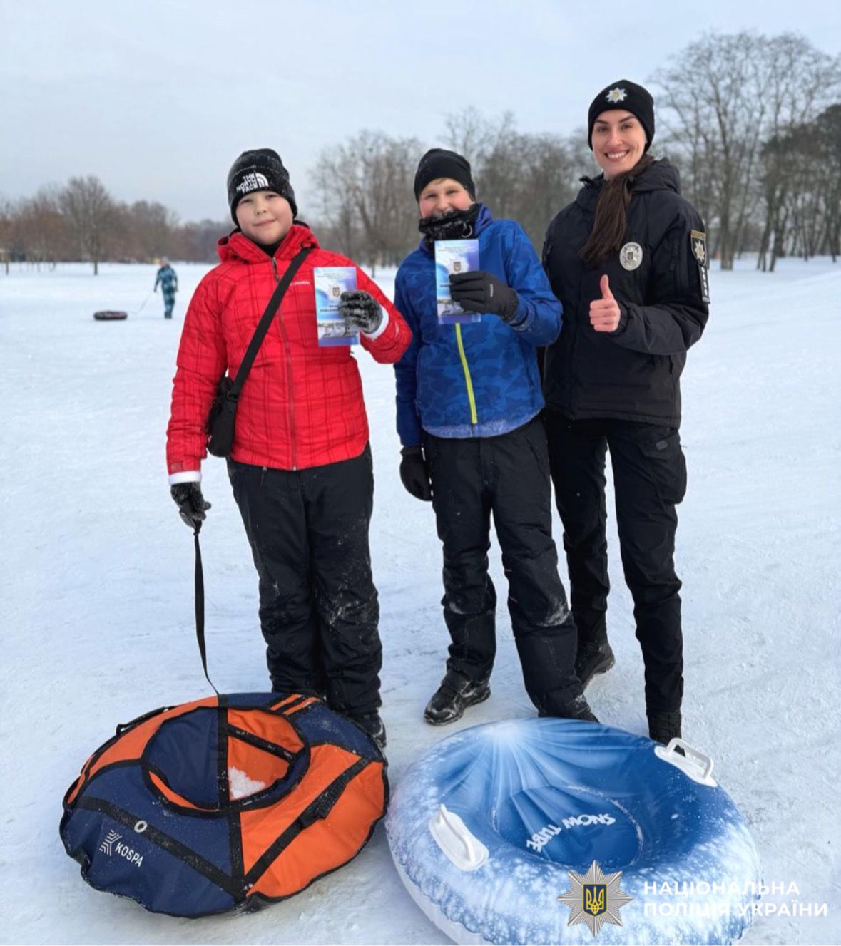 На фотографії зображено ювенальну поліцейську, яка проводить профілактичний захід з дітьми поблизу зимових водойм.