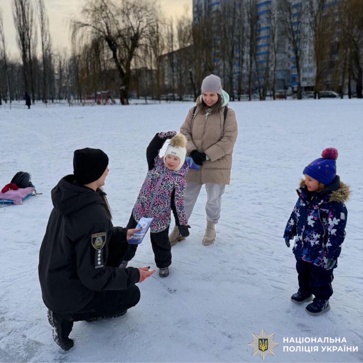 На фотографії зображено ювенальну поліцейську, яка проводить профілактичний захід з дітьми поблизу зимових водойм.