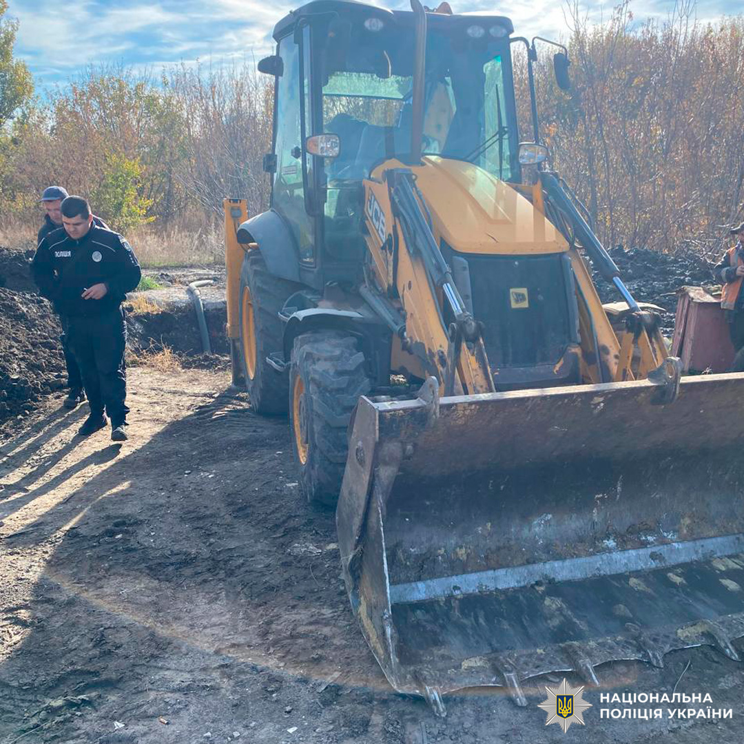 Поліцейський поруч із екскаватором JCB на місці земляних робіт.