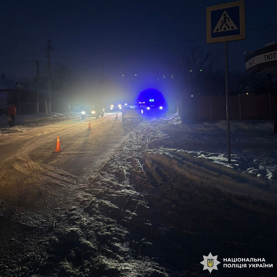 Поліцейський автомобіль із мигалками на місці ДТП серед снігу.