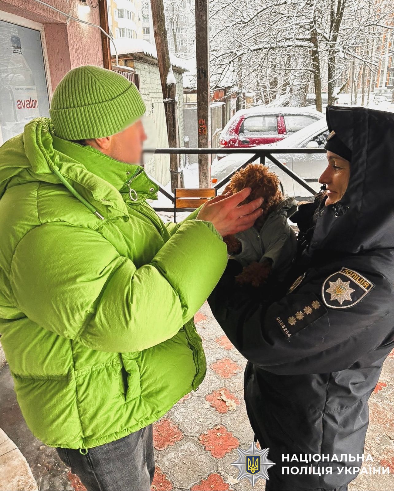 На фотографії зображено поліцейську, яка повертає загубленого песика господарю.