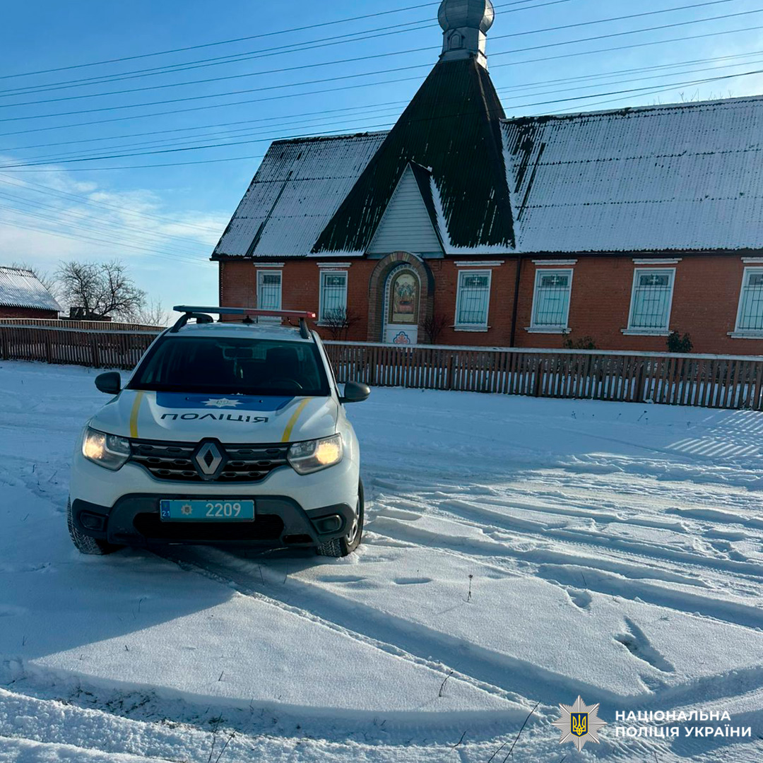 Поліцейський автомобіль біля храму взимку.